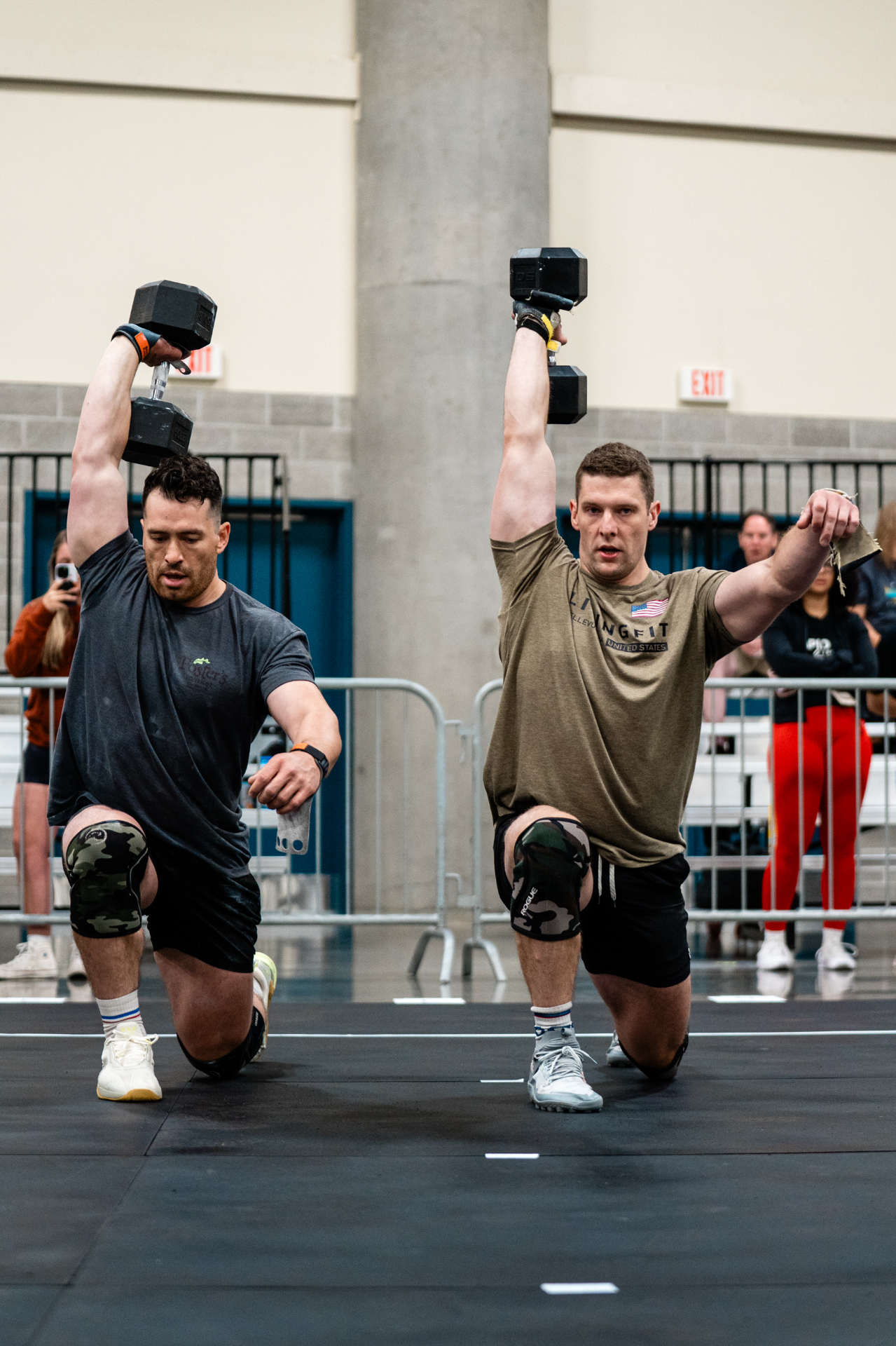 LivingFit athletes performing dumbbell overhead lunges in competition